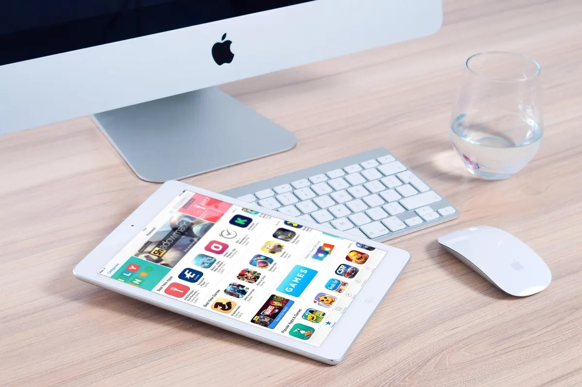 iOS App Development iMac, keyboard and iPad displaying the App Store for iOS app development