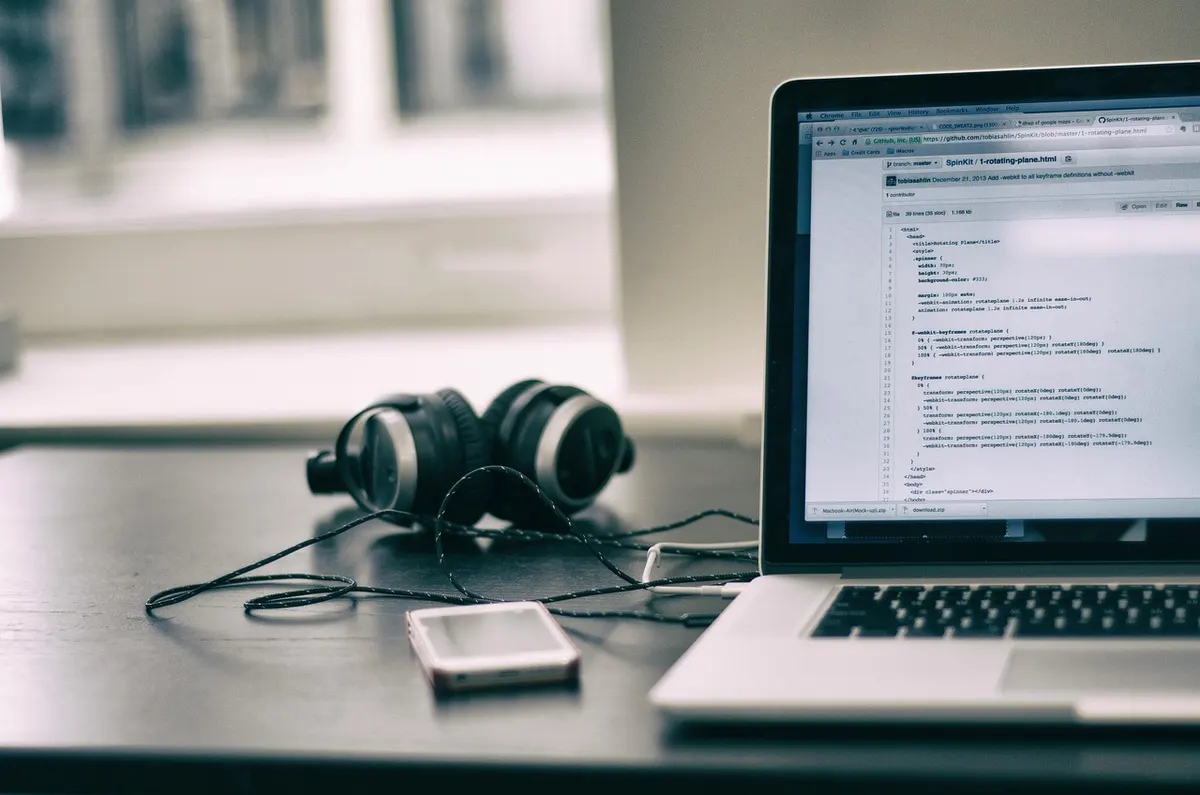 Kotlin for Android Development Laptop displaying source code on GitHub next to headphones on a developer's desk